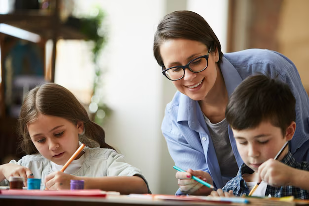 The teacher watches the children draw